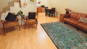 Un salon avec un escalier, un coin repas et une cuisine à l’arrière-plan.