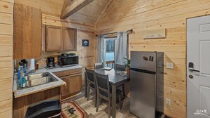 Una cocina compacta con paredes de madera, un refrigerador de acero inoxidable, un microondas y un lavamanos.