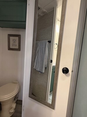 A bathroom with a toilet, a framed sign saying "SPLISH SPLASH", and a towel hanging on a rack. - Beautiful trailer home on 20 acres. Panoramic desert views 18 min from Route 66 (Kingman)
