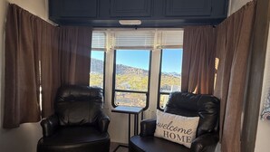 Una habitación con dos sillones de cuero, una mesita y un ventanal con cortinas.