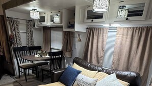 Un interior de caravana acogedor con cama, mesa de comedor y sillas.