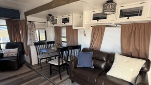 Interior acogedor de una caravana con comedor, sofá de cuero y alfombra.