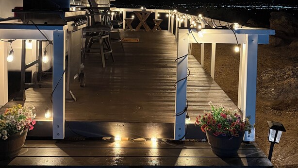 Un espacio de terraza bien iluminado con mobiliario exterior, una parrilla y plantas en macetas.
