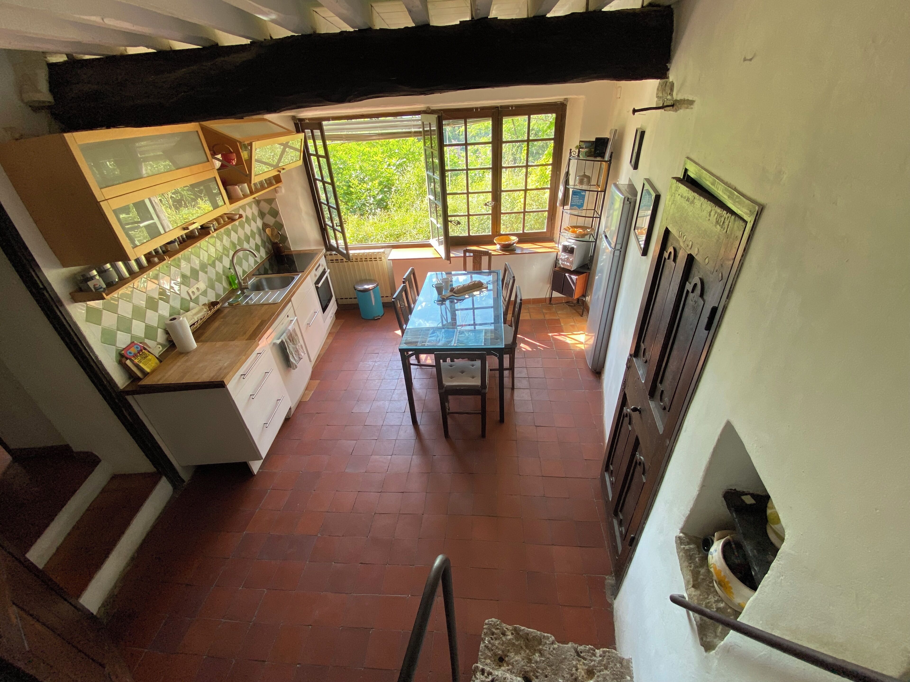 A compact kitchen with a dining area, a window with a view of greenery, and a tiled backsplash.