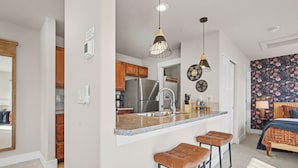 A modern kitchen with a central island, bar stools, and pendant lighting. - The Revive Loft | Balcony, Workspace & Bikes (Fort Collins)