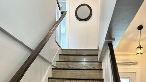 A wooden staircase with white railings and a circular wall decoration. - Wonderful 4-bedroom apartment with AC in peaceful Saco (Saco)
