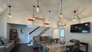A spacious living room with a dining area, a staircase leading to another level, and a mounted TV. - Wonderful 4-bedroom apartment with AC in peaceful Saco (Saco)