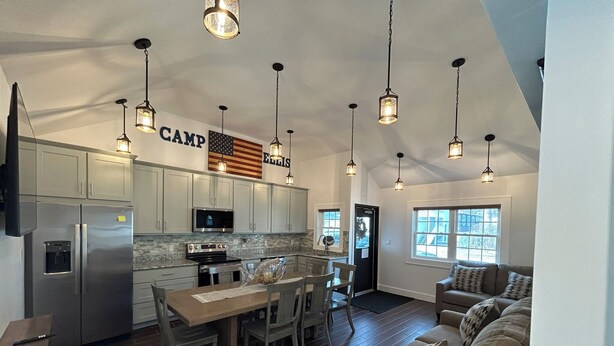 A spacious kitchen with modern appliances, a dining area with a wooden table and chairs, and a cozy living area with a sofa. - Wonderful 4-bedroom apartment with AC in peaceful Saco (Saco)