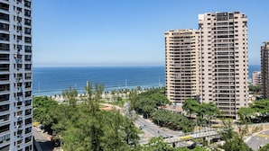 A high-rise building with multiple floors, a view of the ocean, and a road with vehicles. - Barra Max - Praia e Conforto. (Rio de Janeiro)