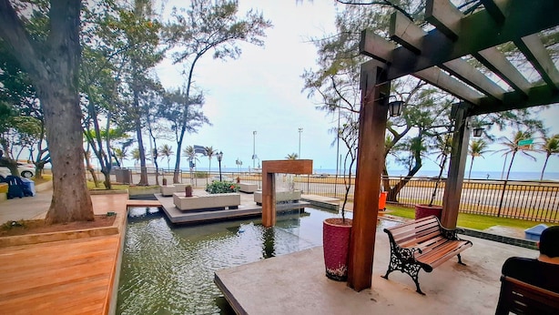 A waterfront park with a wooden deck, benches, and a small water feature. - Barra Max - Praia e Conforto. (Rio de Janeiro)