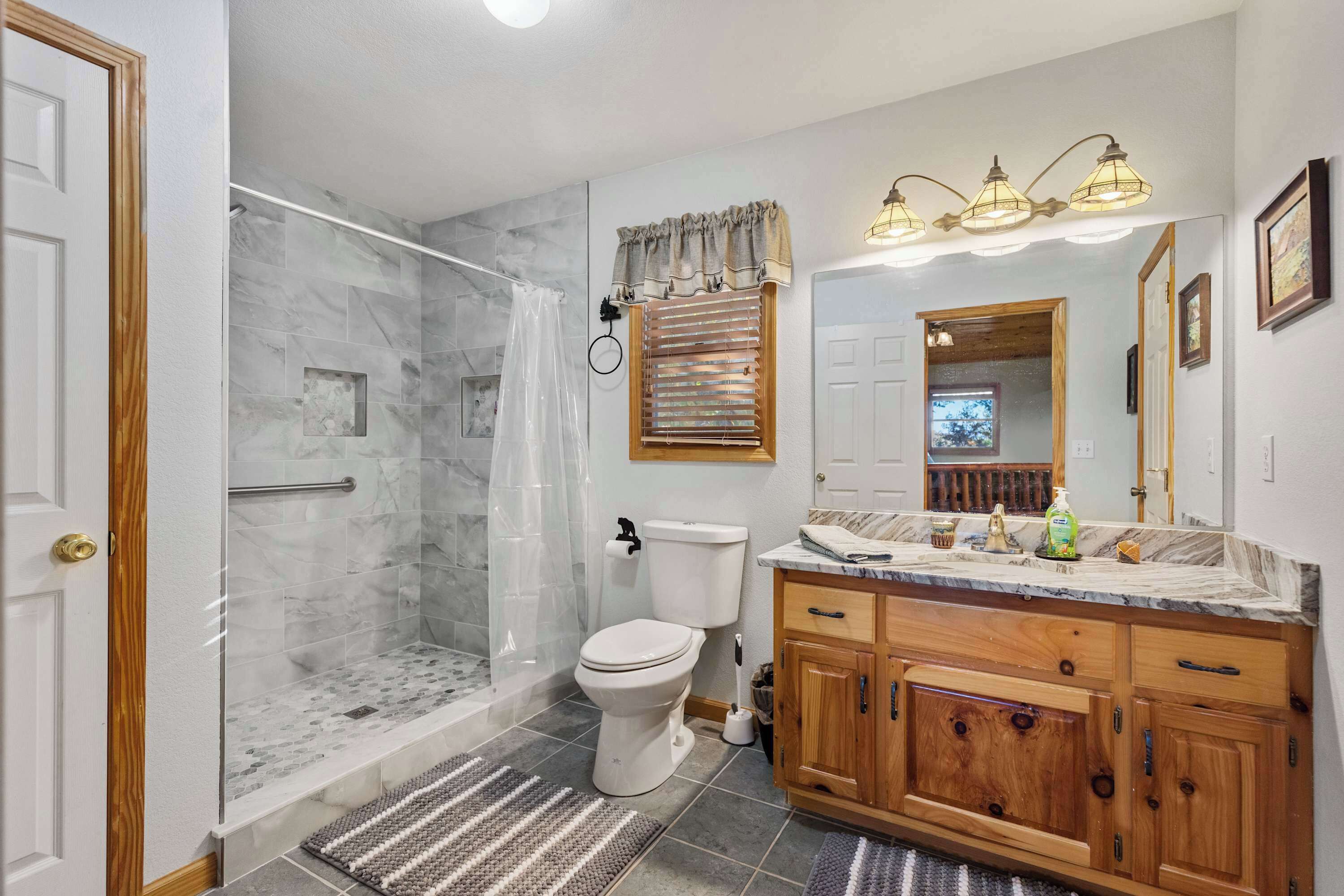 A bathroom with a glass-enclosed shower, a toilet, wooden cabinets, and a vanity with a mirror.