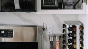 Ett kök med mikrovågsugn, mixer och ett hyllsystem för kryddor.