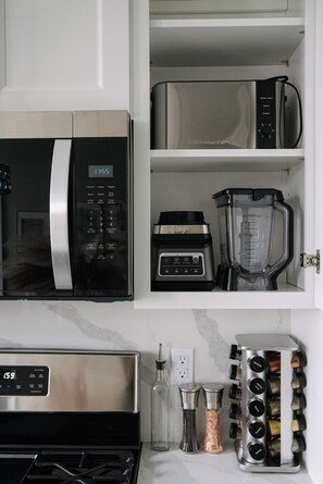 A kitchen with a microwave, blender, and spice rack. - Modern 3BR Near NYC + MetLife • Sleeps 8 + Parking (Union City)
