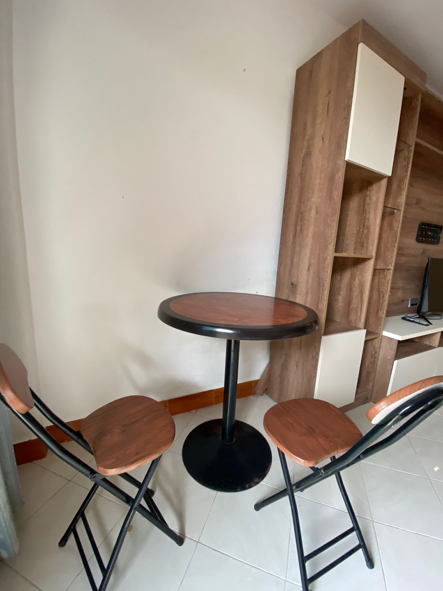 A corner seating area with a round table and four wooden chairs.