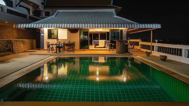 A rooftop pool area with a dining setup and a traditional-style building. - Aksarai Hotel Patong  (Patong)