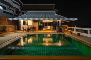 A rooftop pool area with a dining setup and a traditional-style building. - Aksarai Hotel Patong  (Patong)