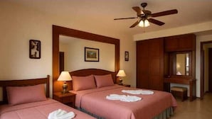 A hotel room with two beds, a ceiling fan, and a wooden wardrobe. - Aksarai Hotel Patong  (Patong)
