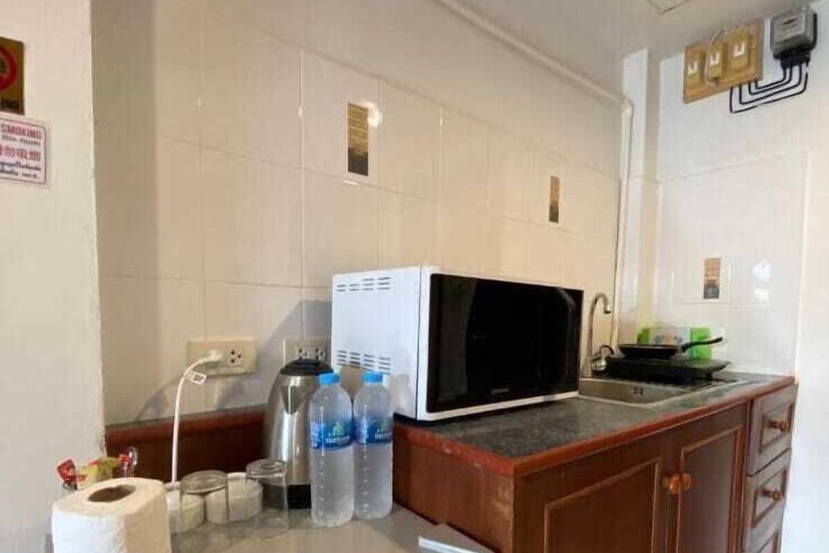 A kitchen with a refrigerator, microwave, and sink.