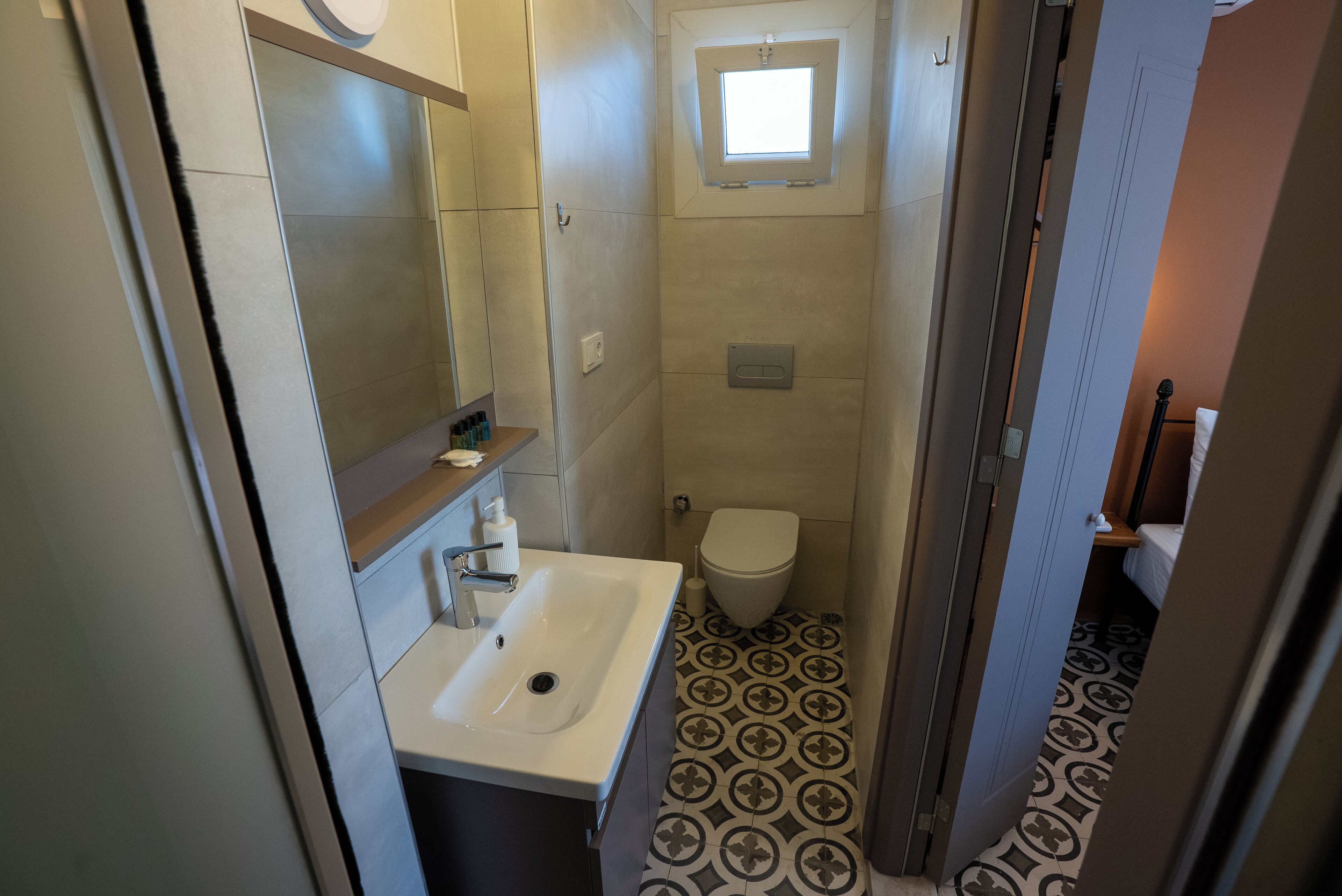 Un baño pequeño con un lavabo blanco, un inodoro y un ventanal.