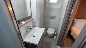 Un baño pequeño y moderno con un lavabo blanco, inodoro y un espejo sobre el lavabo.