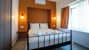 Una habitación de hotel con una cama, dos lámparas de pared, un ventanal con cortinas y un equipo de aire acondicionado.