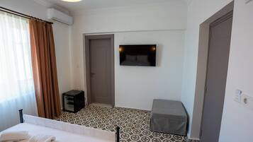 Een hotelkamer met een bed, een televisie, een deur en vloerbedekking met een patroon.