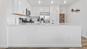Une cuisine moderne avec des meubles blancs, des appareils en acier inoxydable et un îlot central.