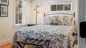 Ein Schlafzimmer mit einem Bett, zwei Fenstern und einem Nachttisch.