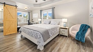 A bedroom with a bed, nightstands, a desk, a chair, a ceiling fan, and a sliding door. - The Bentonville Basecamp (Bentonville)