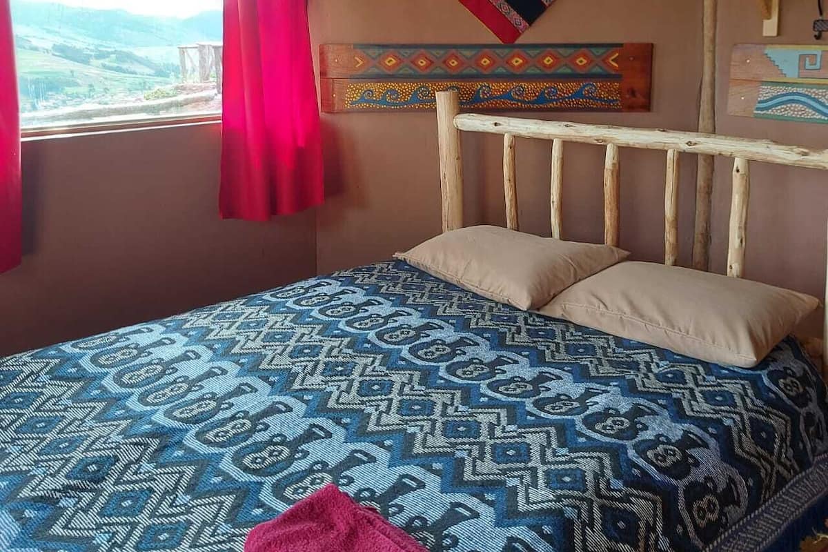 Ein Zimmer mit Bett, einem Fenster mit Blick auf die Landschaft und traditioneller Wandgestaltung.