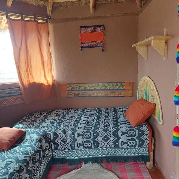 Un dormitorio acogedor con una cama, cabecera, un adorno de pared y una estantería.
