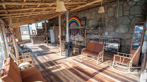 A rustic wooden interior with stone walls, wicker furniture, and a visible fireplace. - Pachamama Hampina Wasi Centro Ancestral - All Inclusive (Maras)
