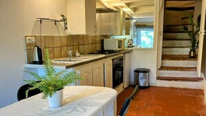 A compact kitchen with a dining area, including a table with chairs, a kettle, a microwave, and a sink.