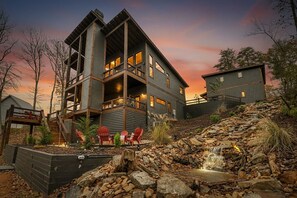A modern multi-story building with a stone waterfall feature in the foreground. - A Great Escape - Modern Cabin w/ views & waterfall (Blue Ridge)