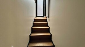 Una escalera que lleva a una puerta con un panel de vidrio satinado.