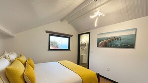 Un dormitorio con cama, almohadas, ventana, cuadro y espejo.