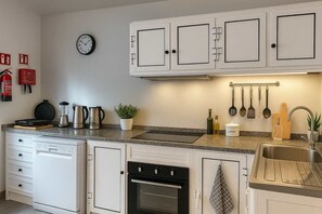 A kitchen with white cabinets, a clock, a coffee maker, a kettle, a toaster, a plant, and various kitchen utensils. - Beachside House in Machico w/ Private Balcony (Machico)