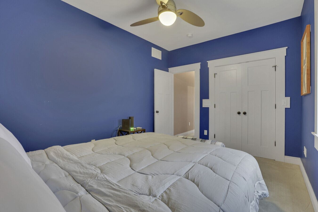 A bedroom with a bed, a ceiling fan, and a desk with a computer.
