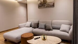 A modern living room with a grey sofa, a round coffee table, and a patterned rug. - 3-bedroom apartment in enchanting Cairo Governorate with AC (Cairo Governorate)
