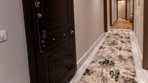 A hallway with a dark wooden door, recessed lighting, and a patterned carpet. - 3-bedroom apartment in enchanting Cairo Governorate with AC (Cairo Governorate)