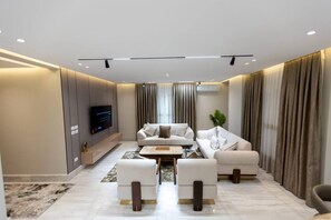 Una sala de estar moderna con un conjunto de sofás, una mesa de centro y un televisor de pantalla plana montado en la pared.