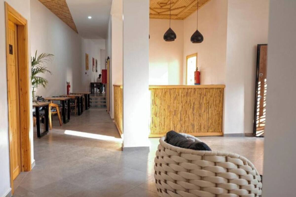 Un pasillo con puerta de madera, una silla de mimbre y una zona de recepción con pared de bambú.