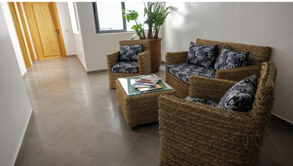 Una sala de estar con muebles de mimbre, una mesa de centro y una planta en maceta.