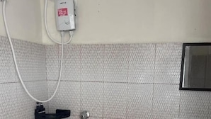 A small bathroom with a shower, a toilet, a sink, and a bucket. - Baden Powell Hostel  (Baguio)