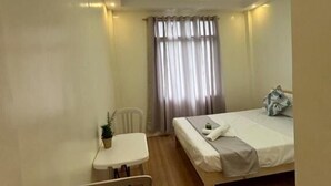 A small, clean room with a single bed, a small table, and a chair. - Baden Powell Hostel  (Baguio)