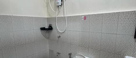 A small bathroom with a toilet, bidet, and a shower head mounted on the wall.