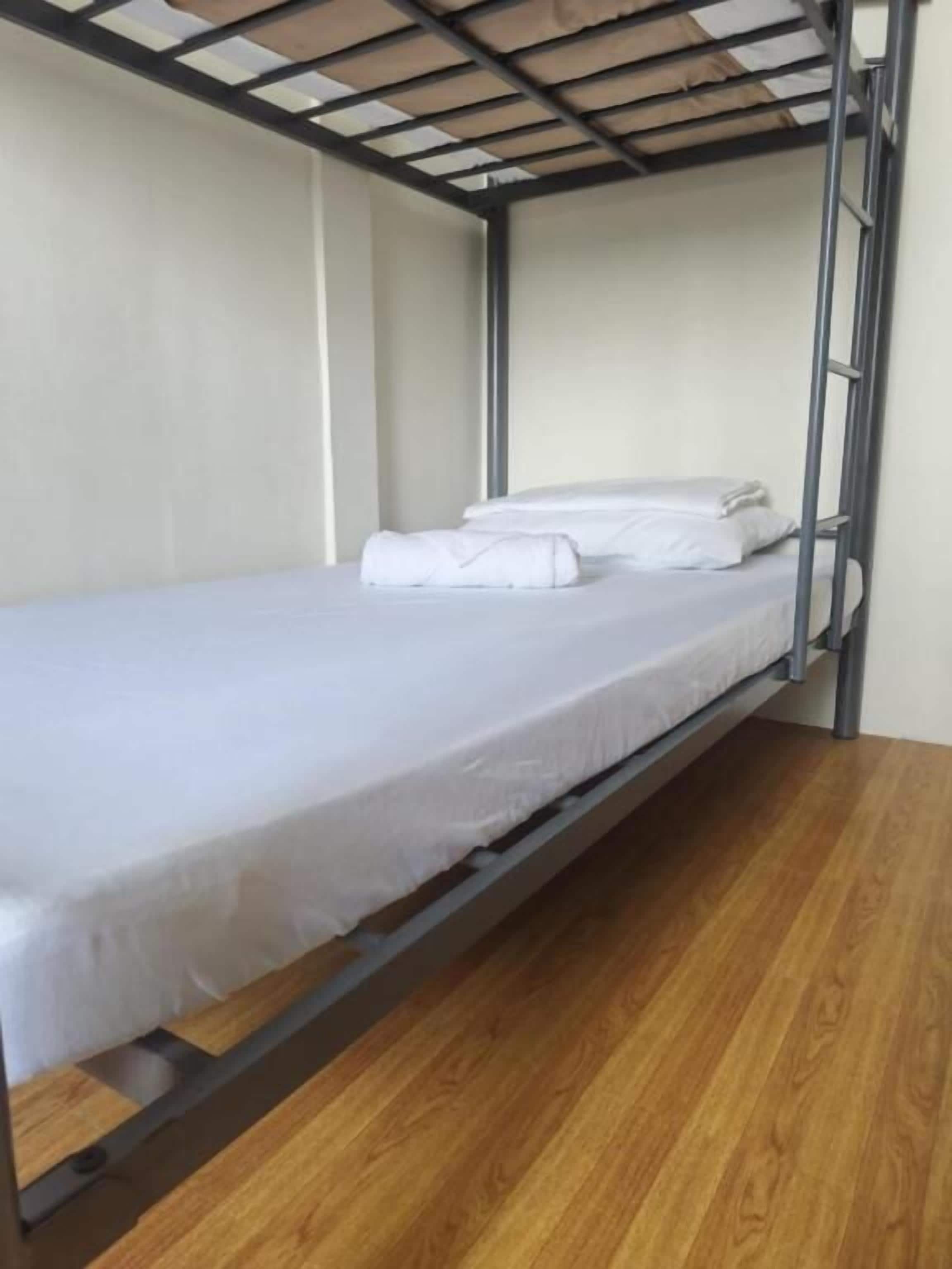 Ein Einzelstockbett mit Metallgestell und Holzboden.