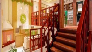 Un interior espacioso con una escalera de madera, un mostrador de recepción y un área de descanso.