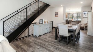 Una cocina moderna con comedor, que presenta una escalera con barandilla negra y un armario blanco con adornos.
