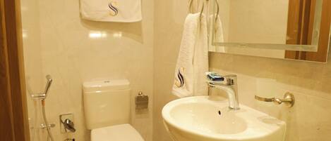 A modern bathroom with a toilet, sink, and mirror.